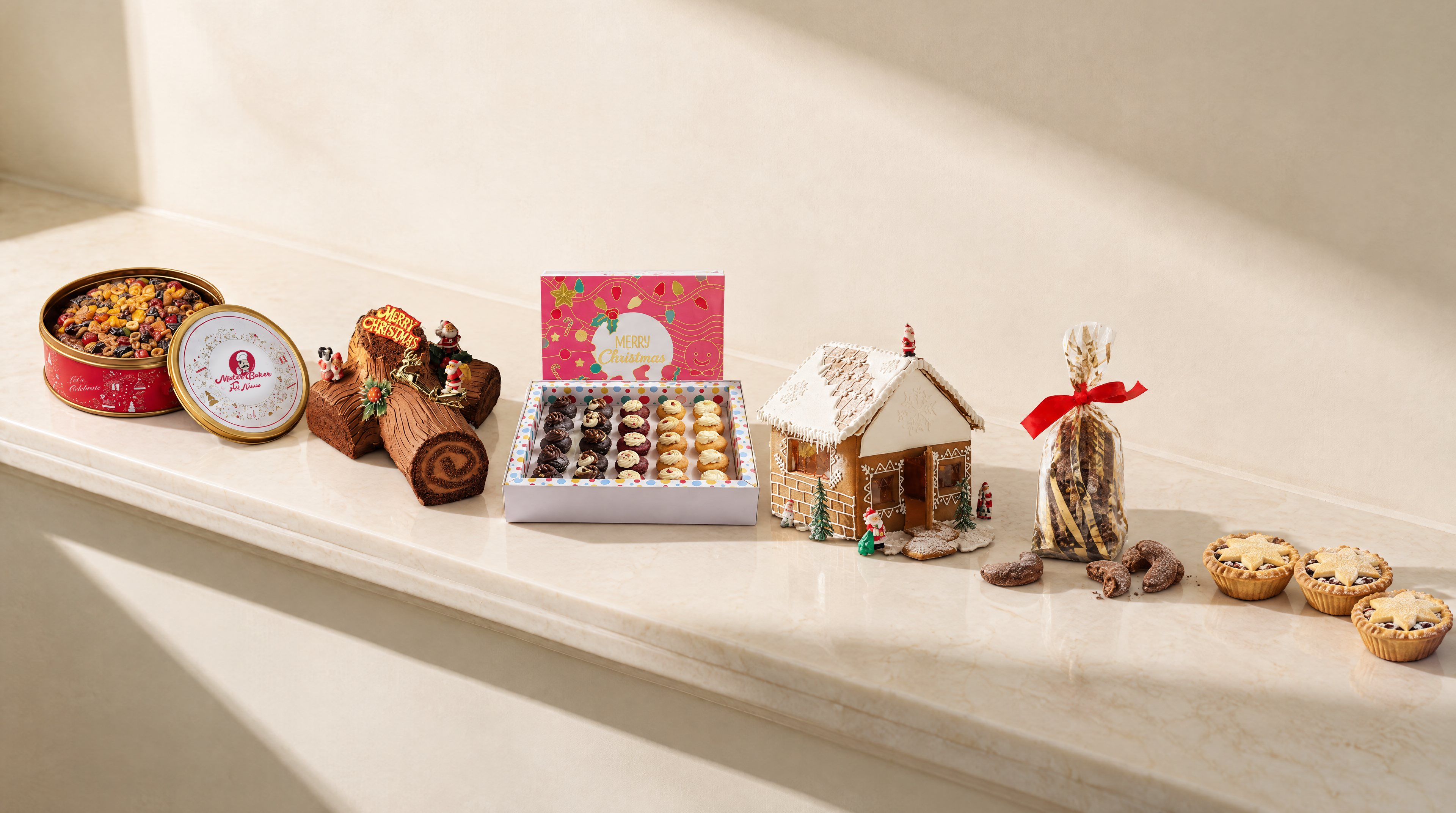 Mister Baker plum cake, yule log, mini cupcakes, gingerbread house, brunsli cookies and mince pies on a marble counter